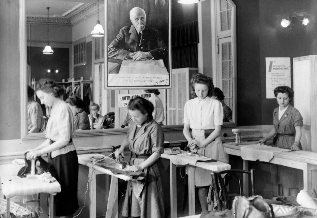 À Vichy, en 1942, sous une photographie du maréchal Pétain, des femmes prennent part à une séance de repassage organisé par le Secours national. KEYSTONE-FRANCE/GAMMA-RAPHO